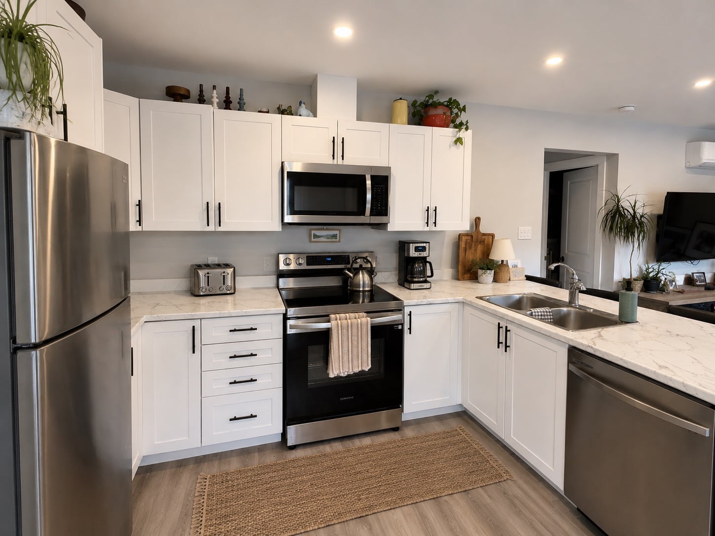 Bright, fully finished kitchen in a real Visture-built coach home (ADU) in Peterborough, with stainless appliances and quartz counters